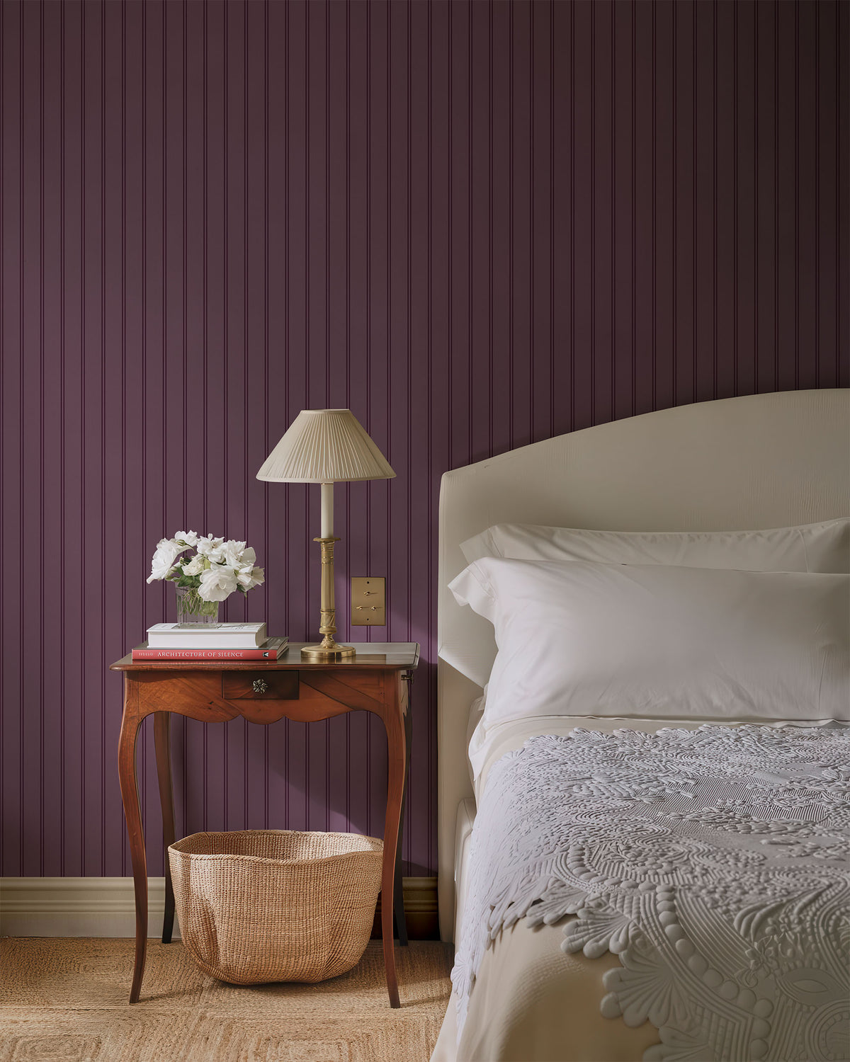 Bedroom with purple striped wallpaper, wooden side table, and bed with white bedding.